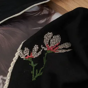 Detailed view of black vintage embroidered headscarf with floral patterns and lace trim.
