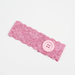Gedetailleerd overzicht van de roze kanten haarband met grote knop en decoratieve rand.