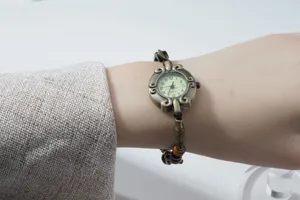 Vintage bronze beaded bracelet watch detail, elegant retro design with charm for women.