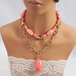Vista detallada del collar multicapa de cuentas rosas y cadena dorada con gran colgante.