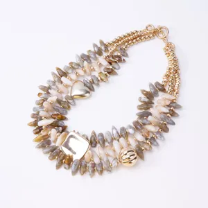 Collar multicapa de conchas y cuentas de piedra con colgantes dorados de corazón y cuadrado.