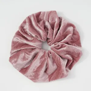 Close-up detail view of the soft pink velvet hair scrunchie, showing plush fabric texture.