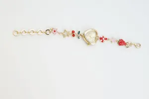 Close-up detail shot of a gold heart charm watch with cute strawberry and flower charms.