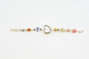 Detailed view of women's irregular gold watch bracelet with ceramic and enamel beads.