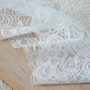 White elastic lace trim detail, delicate floral hollow pattern close-up for DIY crafting.