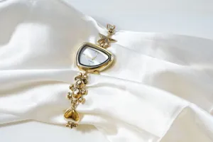 Golden irregular watch detail showing unique star, bear charm and white dial design.