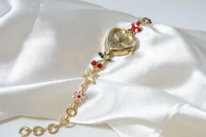 Heart-shaped quartz watch detail shot, featuring cute cherry and flower charm bracelet design.