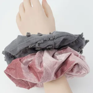 Detailed view of two elegant hair scrunchies, featuring grey fabric and pink velvet style.