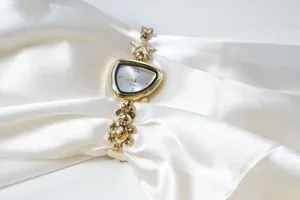 Detail view of a chic gold watch with irregular dial, cute bear and star charms on strap.