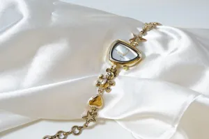 Gold irregular dial bracelet watch with cute bear and star charms, chic vintage style detail.