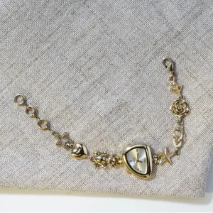Gold irregular face watch bracelet with cute teddy bear, heart, star, and rose charms.