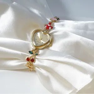 Gold heart-shaped quartz watch featuring cute cherry and mushroom charms on white satin fabric.
