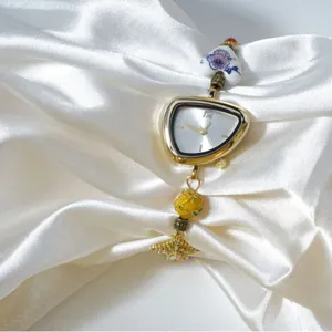 Women's gold irregular dial quartz watch with ceramic and enamel bead handmade strap.