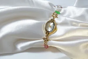 Close-up detail of women quartz watch with pearl flower beaded bracelet strap on white silk.
