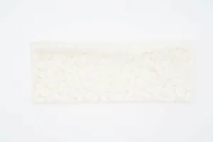 Vista dettagliata della fascia in pizzo bianco con delicati motivi floreali e consistenza elastica.