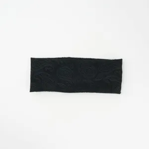 Detailed shot of a black knitted headband with a classic paisley pattern, soft texture.