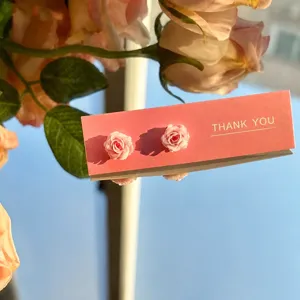 Boucles d'oreilles clous fleur camélia dégradé gros plan, design bijoux floraux roses doux.