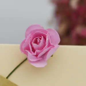 Primer plano de detalle de una rosa de papel rosa en tarjeta para decoración DIY.