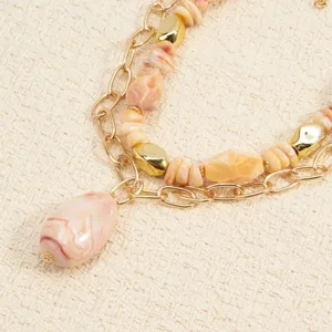 Primer plano de collar de cuentas multicapa con piedras jaspeadas rosas y cadena oro.
