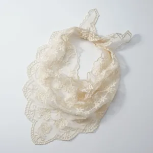 Close up of beige lace floral embroidered triangle scarf, delicate hollow out design detail.