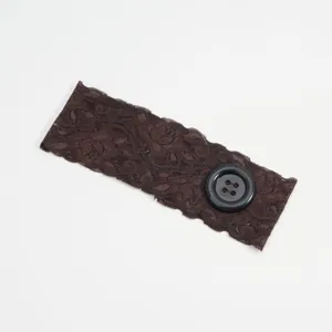 Bruine kant hoofdband detail, met zachte florale kant textuur en een grote decoratieve knop.