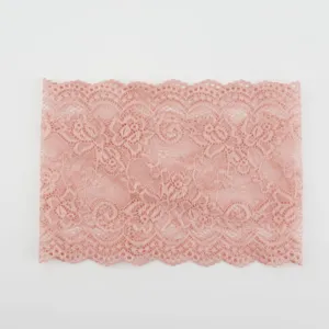 Detail van de brede roze kantband met een fijn bloemmotief en geschulpte rand.