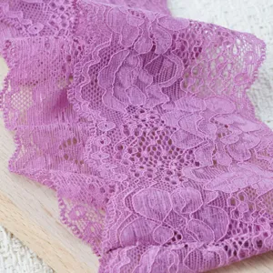 Nahaufnahme von violettem elastischem Spitzenband mit zarter, filigraner Blumenmusterstruktur.