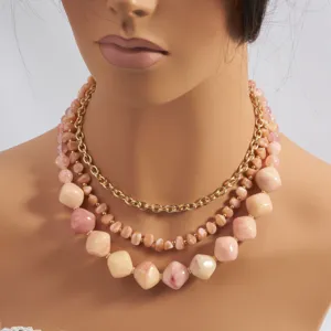 Gedetailleerd overzicht van de gelaagde boho roze steen en gouden ketting voor strandfeest.