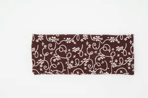 Gros plan détaillé du bandeau tricoté rétro à fleurs marron, texture douce et motif clair.