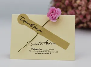 Primer plano de tarjeta de felicitación de papel kraft vintage con flor rosa seca y texto.