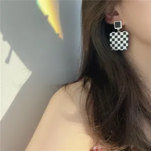 Checkerboard square ear detail shot, geometric contrast design, elegant women jewelry piece.