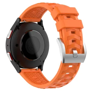 Close-up detail of orange silicone watch strap with tire tread texture and silver buckle.