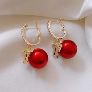 Gold hoop earrings featuring sparkling crystals, a cute bow, and glossy red pearl detail.
