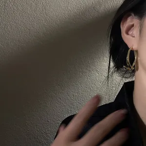 Detailed view of minimalist curved C-shaped metal earrings, highlighting the sleek back-hanging design.