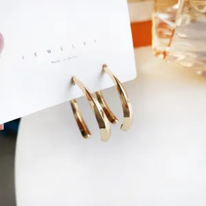 Gold curved C-shaped hoop earrings, elegant minimalist metal ear jewelry detail view.