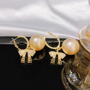 Exquisite pearl bow earrings detail shot, stylish gold hoop design with sparkling diamonds.