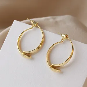 Minimalist gold metal curved C-shaped back-hanging earrings detail view, elegant jewelry.