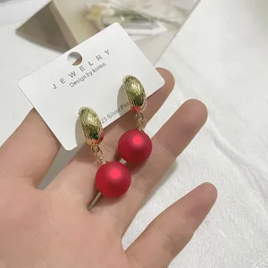 Nahaufnahme von roten matten Perlenohrringen mit goldener texturierter C-Creole und Silber.