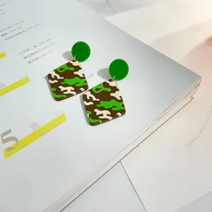 Detailaufnahme von trendigen acryl geometrischen camouflage ohrringen mit grünen steckern.