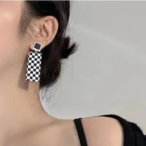 Close-up detail of trendy black and white checkerboard geometric earrings with silver needle.