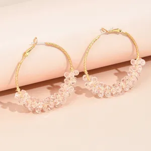 Vue détaillée de créoles dorées ornées de grappes de perles de cristal roses étincelantes.