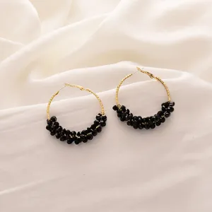 Gros plan détaillé de boucles d'oreilles créoles dorées élégantes ornées de perles de cristal.