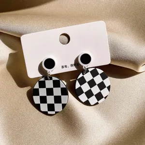 Classic black and white checkerboard earrings, geometric round design, elegant vintage style detail.