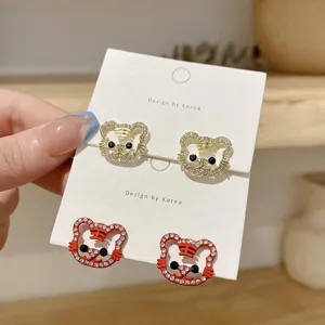 Close-up detail of cute tiger rhinestone earrings in gold and red on a white card display.