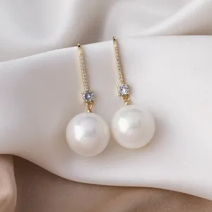 Elegant pearl drop earrings detail with sparkling cubic zirconia and gold-plated finish.