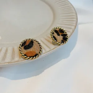 Close-up of vintage leopard print round stud earrings with gold twisted metal border detail.
