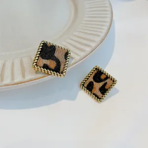 Detailed shot of square leopard print earrings featuring a twisted gold metal border chic accessory.