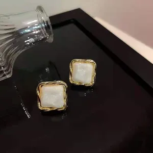 Elegante quadratische Ohrringe mit weißer Muscheltextur und Goldrand für Damen.