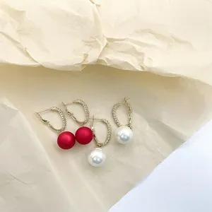 Detailed view of elegant C-shaped hoop earrings with red and white pearls, chic jewelry.