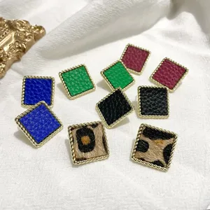 Detailed close-up shot of geometric square earrings featuring colorful leather and chic leopard print.